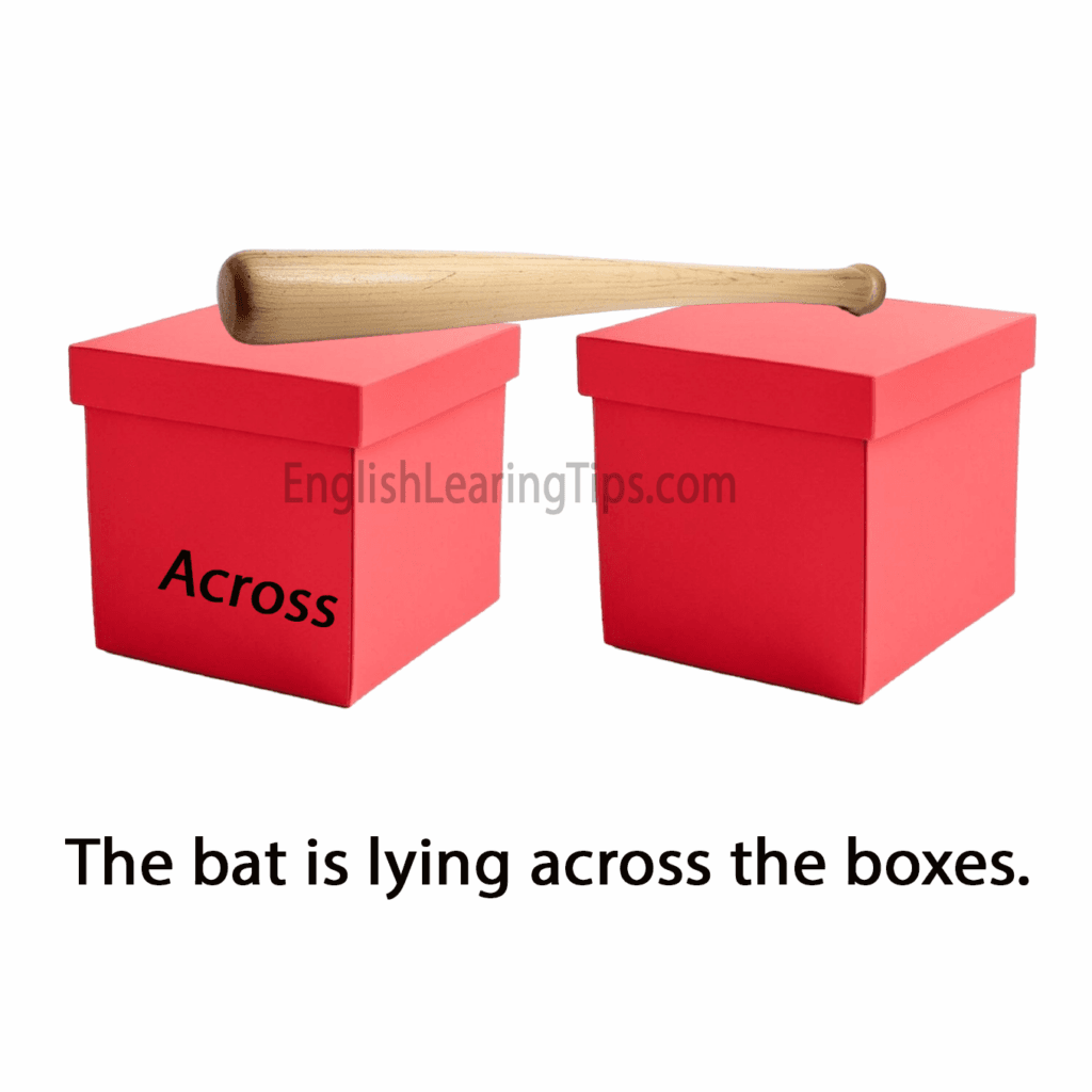 A wooden bat lying across two red boxes, demonstrating the preposition of position "across"