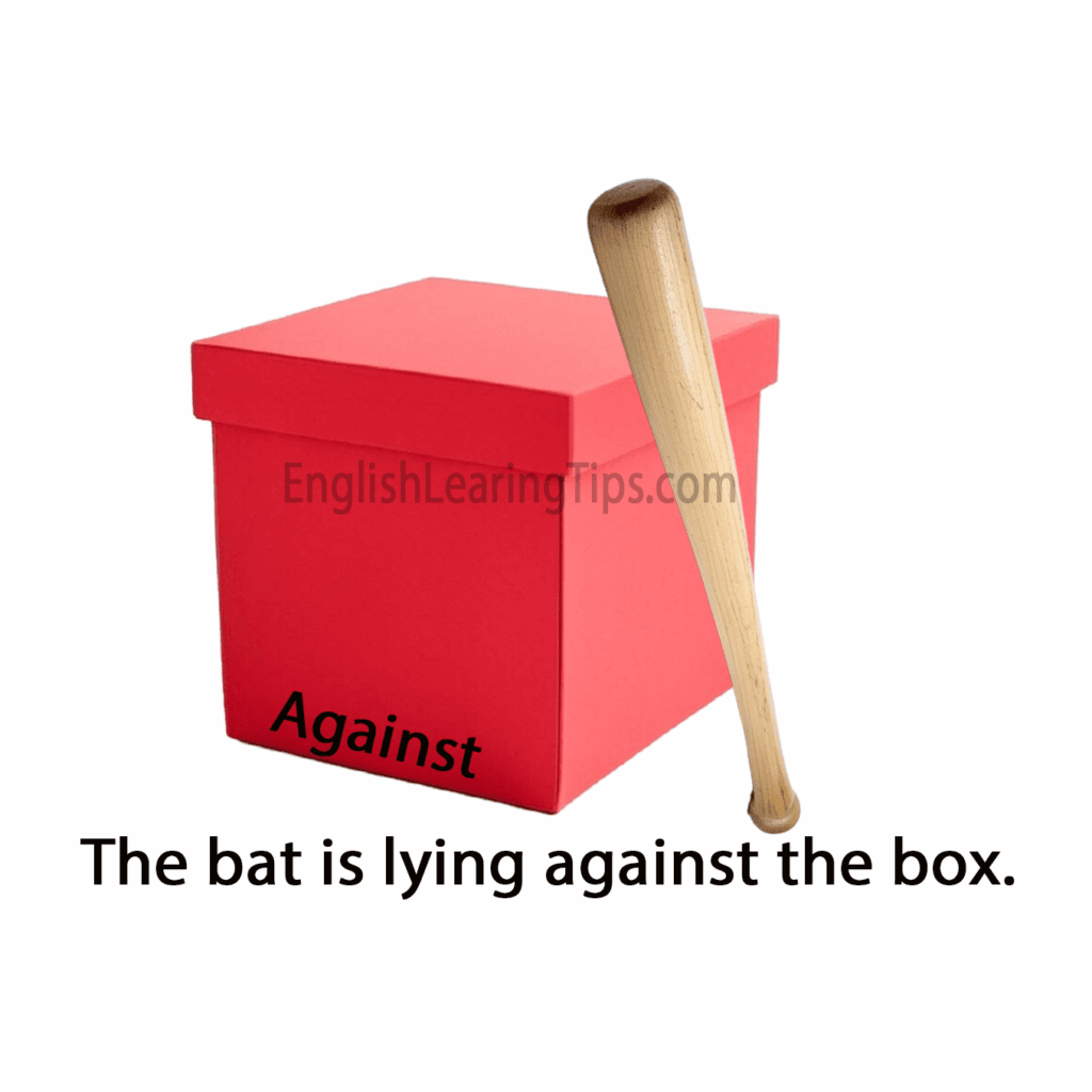 A wooden bat leaning against a red box, illustrating the preposition of position "against"