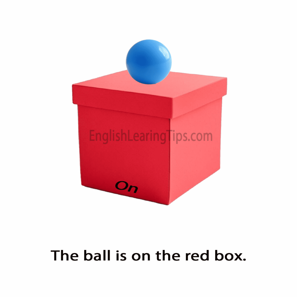 A blue ball resting on the top surface of a red box, illustrating the preposition of position "on"