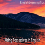 A landscape of mountains and a lake at sunset with the text "Using Possessives in English"