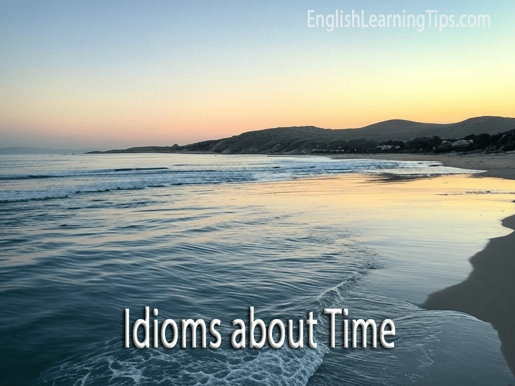 A peaceful beach at sunrise with the text "Idioms about Time" overlaid in the foreground.