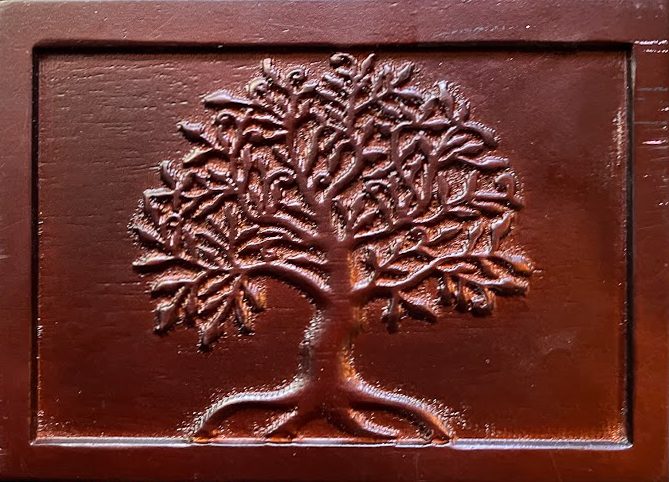 A dark mahogany wooden cremation urn for a dog featuring a hand-carved tree of life design.
