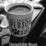 A black and white photo of a mug containing coffee with the word "coffee" overlaid. The mug features text that reads "My favorite person is my dog" to illustrate the difference between uncountable and countable nouns.