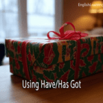 A wrapped Christmas gift on a wooden table with text overlay reading "Using Have/Has Got."