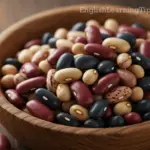A wooden bowl filled with various colorful dried beans, illustrating the British idiom "full of beans."