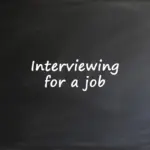 A dark chalkboard with the white handwritten text "Interviewing for a job" centered on the surface.