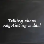 Text on a blackboard that reads: Talking about negotiating a deal.