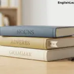 A simple stack of three books labeled Nouns, Adverbs, and Grammar on a wooden desk with a fountain pen.