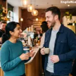 A man and a woman smiling and engaging in friendly small talk while holding coffee cups in a modern cafe setting.